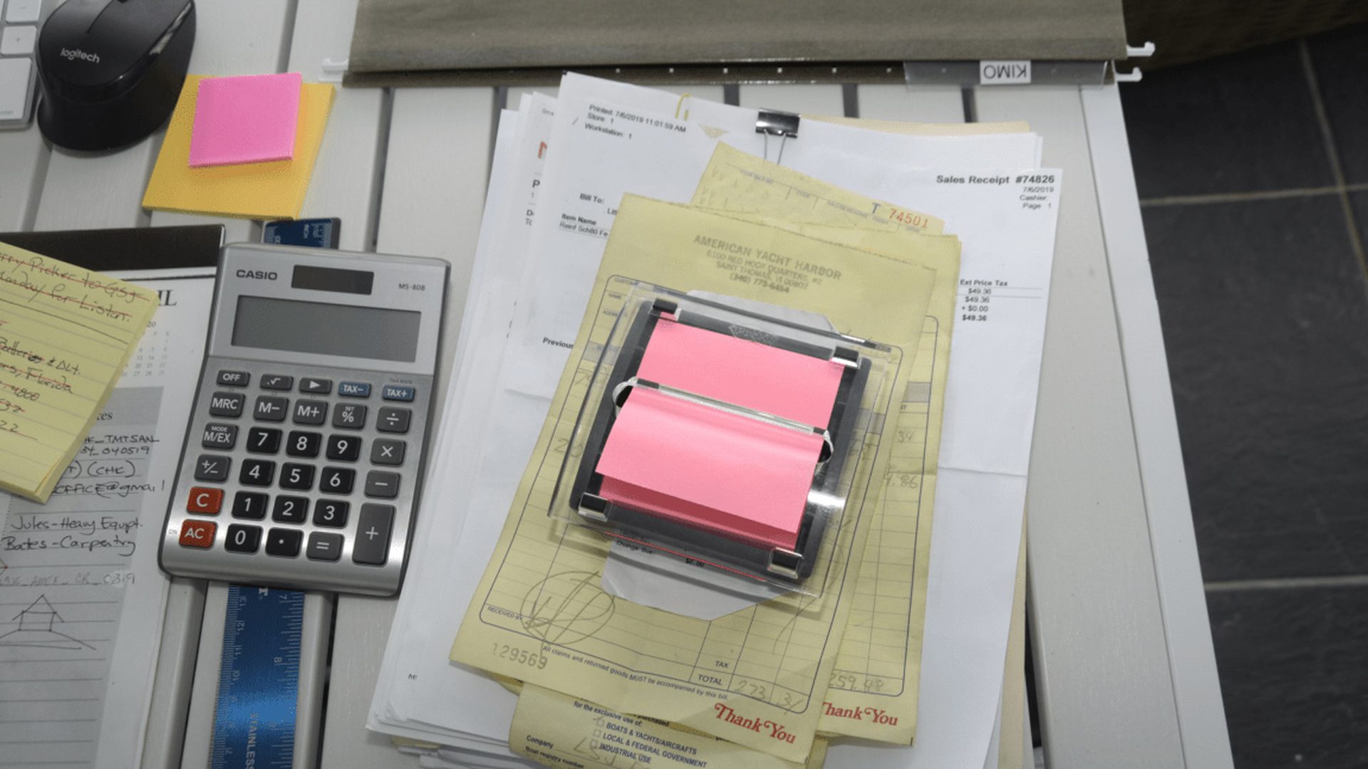 EFTA00003028-Beach-House - Cluttered desk with papers sticky notes a calculator and a mouse suggesting busy work