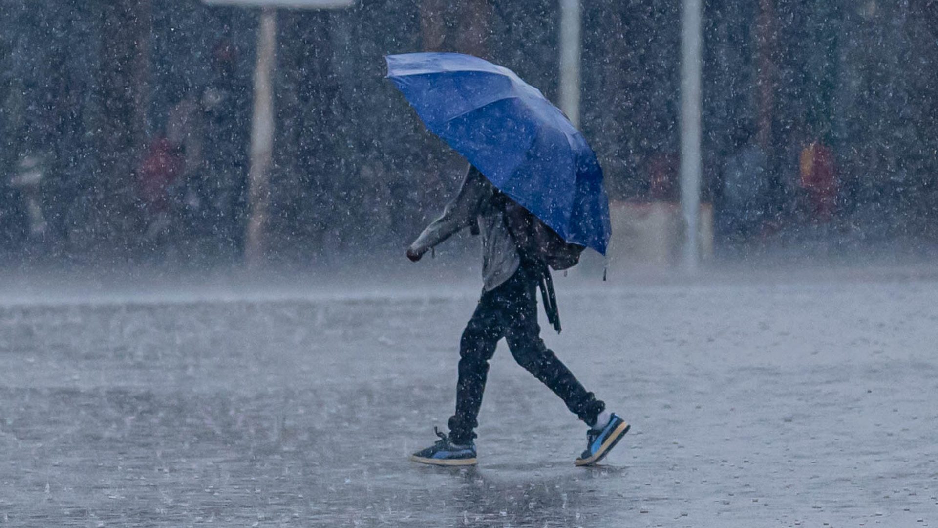 A man walks through heavy rain under an umbrella in Kigali, Rwanda. Emmanuel Kwizera